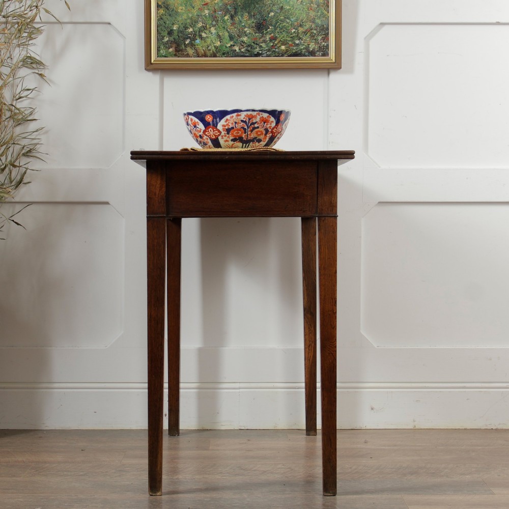 A George III Georgian oak side table featuring a single drawer with a brass handle plate and four square tapered legs. View XI