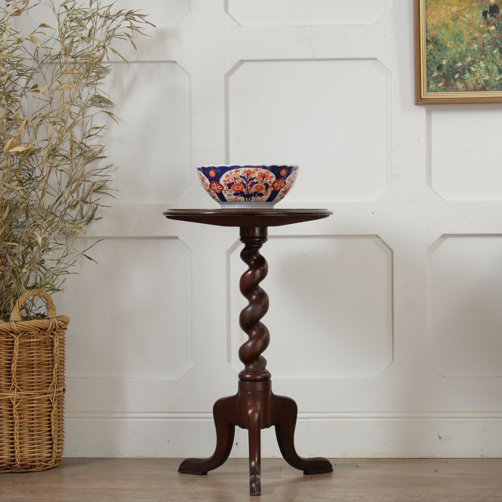 A Victorian dark walnut pedestal table featuring a circular top, a central barley twist turned column, and a tripod base.