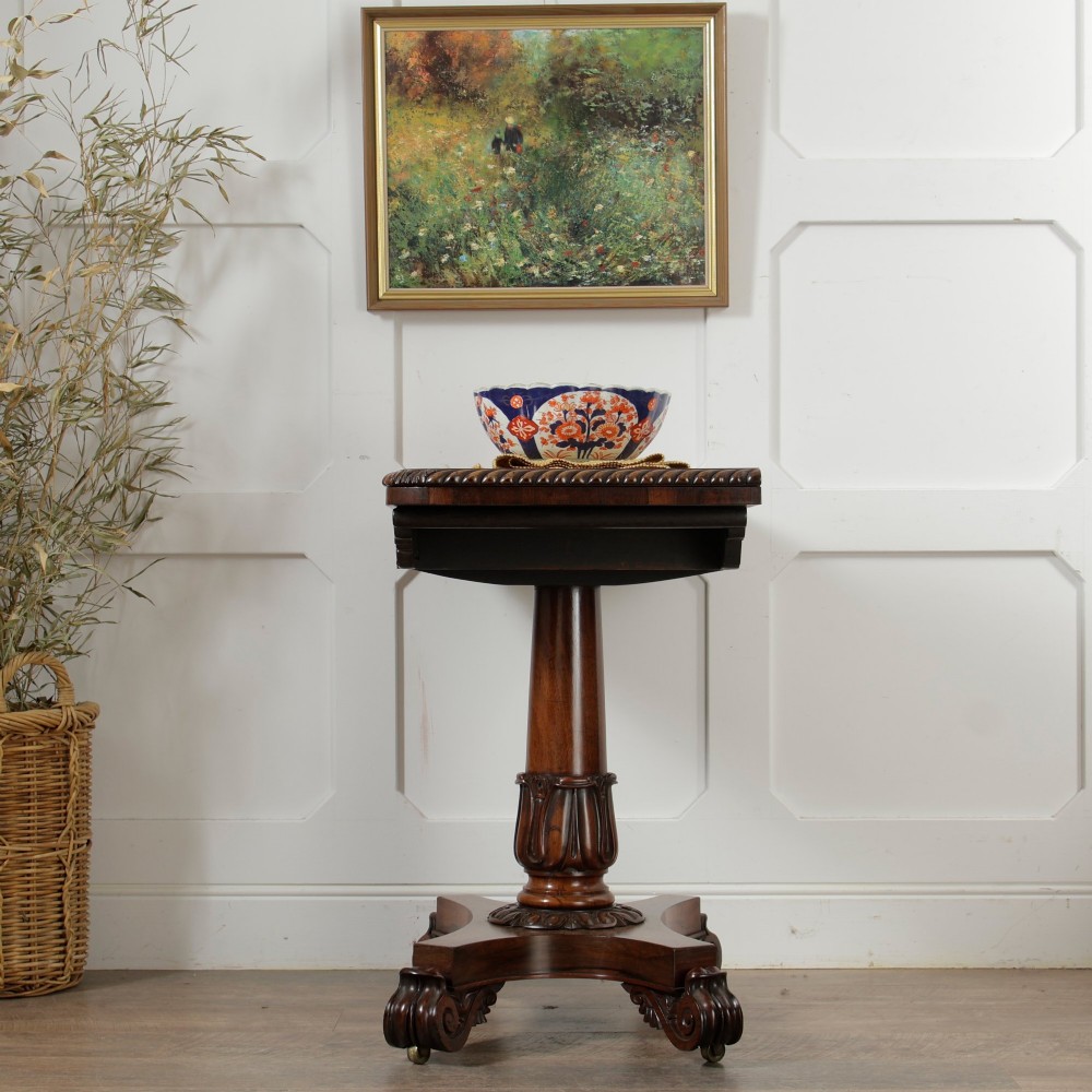A William IV dark rosewood card table featuring a pedestal stem, carved scroll feet on castors, and a gadrooned top edge. View III