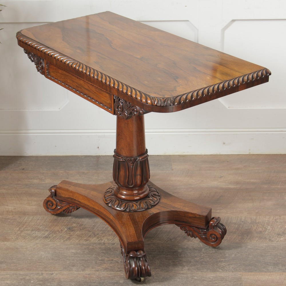 A William IV dark rosewood card table featuring a pedestal stem, carved scroll feet on castors, and a gadrooned top edge. View V