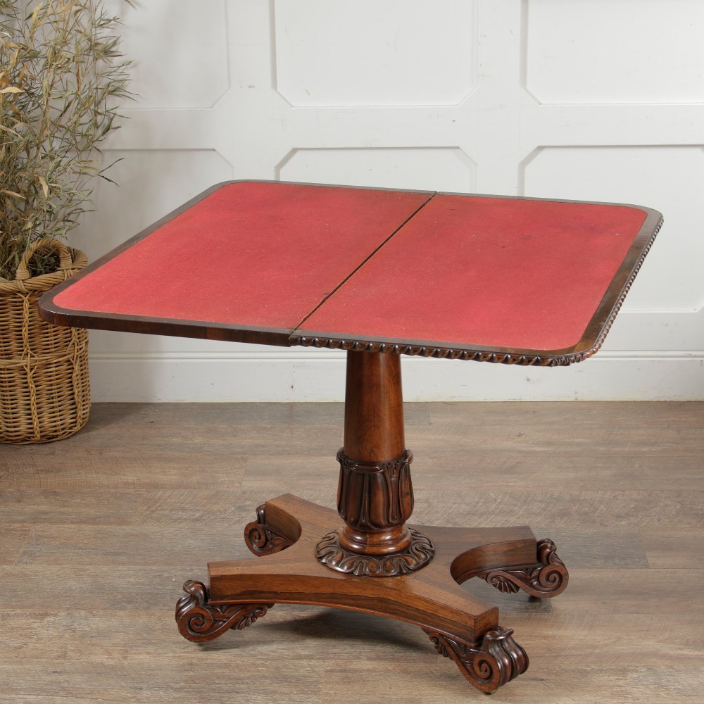 A William IV dark rosewood card table featuring a pedestal stem, carved scroll feet on castors, and a gadrooned top edge. View VI