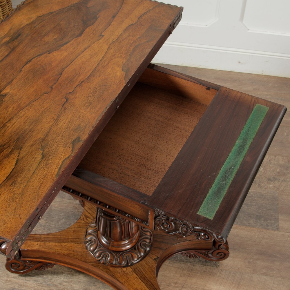 A William IV dark rosewood card table featuring a pedestal stem, carved scroll feet on castors, and a gadrooned top edge. View VII