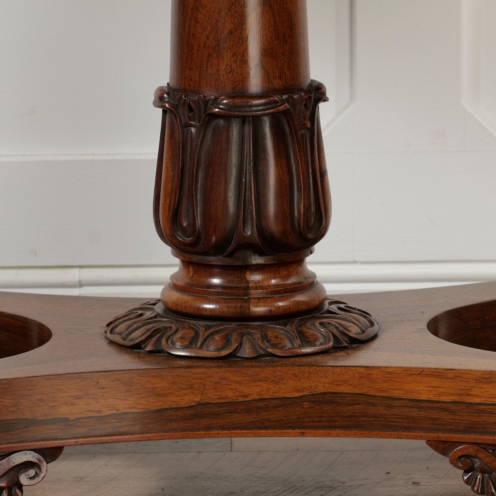 A William IV dark rosewood card table featuring a pedestal stem, carved scroll feet on castors, and a gadrooned top edge. View IX