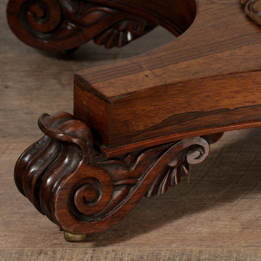 A William IV dark rosewood card table featuring a pedestal stem, carved scroll feet on castors, and a gadrooned top edge. View XI
