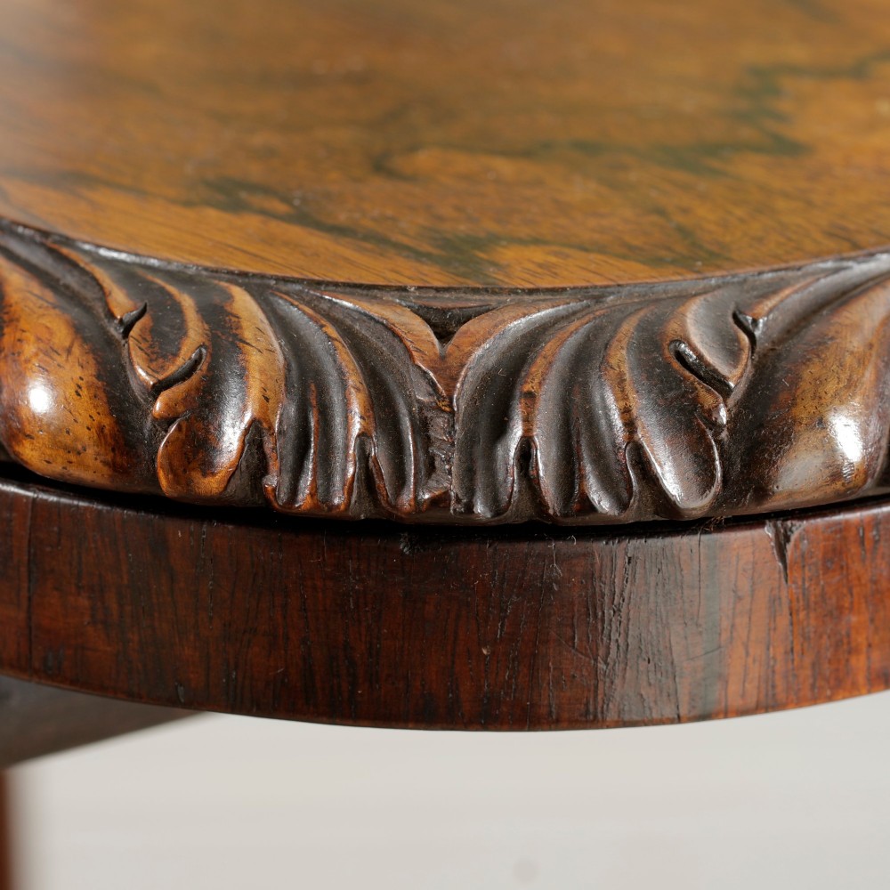 A William IV dark rosewood card table featuring a pedestal stem, carved scroll feet on castors, and a gadrooned top edge. View XII