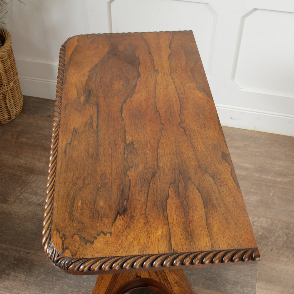 A William IV dark rosewood card table featuring a pedestal stem, carved scroll feet on castors, and a gadrooned top edge. View XV