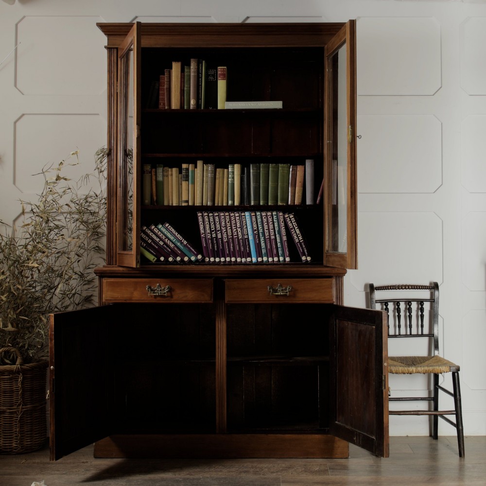 A late Victorian wooden glazed bookcase featuring two upper glass doors above two drawers and a double-door cupboard carved with floral urn motifs. View III