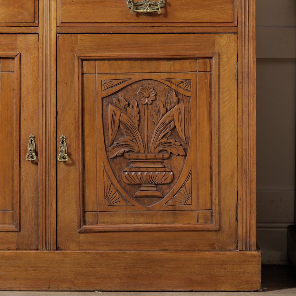 A late Victorian wooden glazed bookcase featuring two upper glass doors above two drawers and a double-door cupboard carved with floral urn motifs. View IV