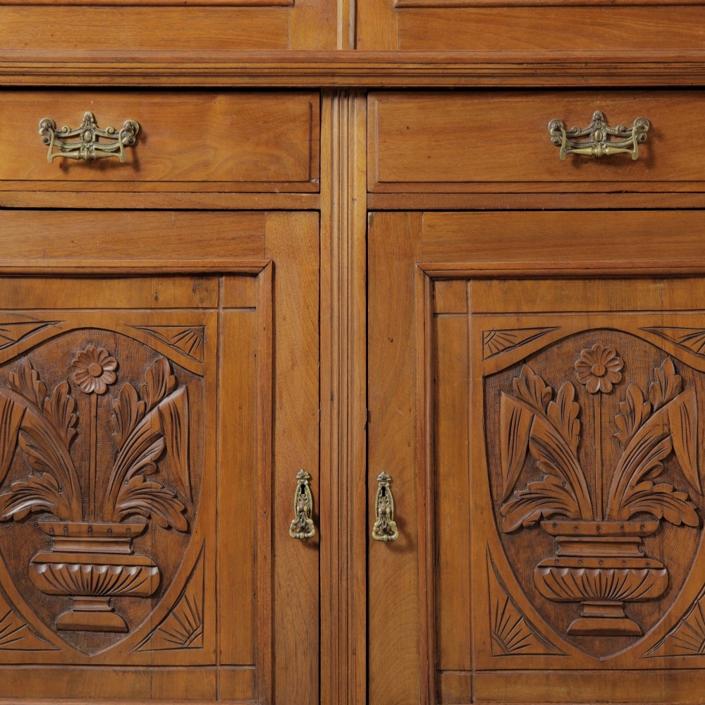 A late Victorian wooden glazed bookcase featuring two upper glass doors above two drawers and a double-door cupboard carved with floral urn motifs. View VI