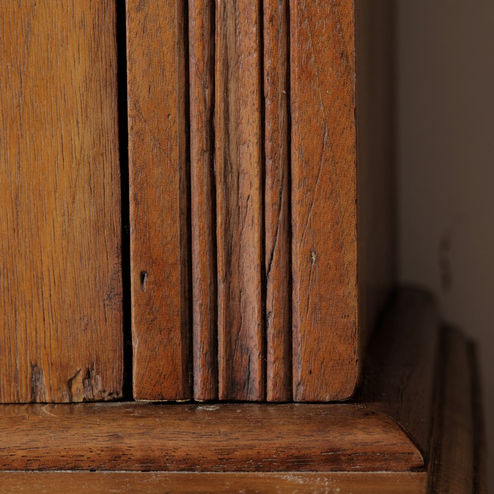 A late Victorian wooden glazed bookcase featuring two upper glass doors above two drawers and a double-door cupboard carved with floral urn motifs. View VIII