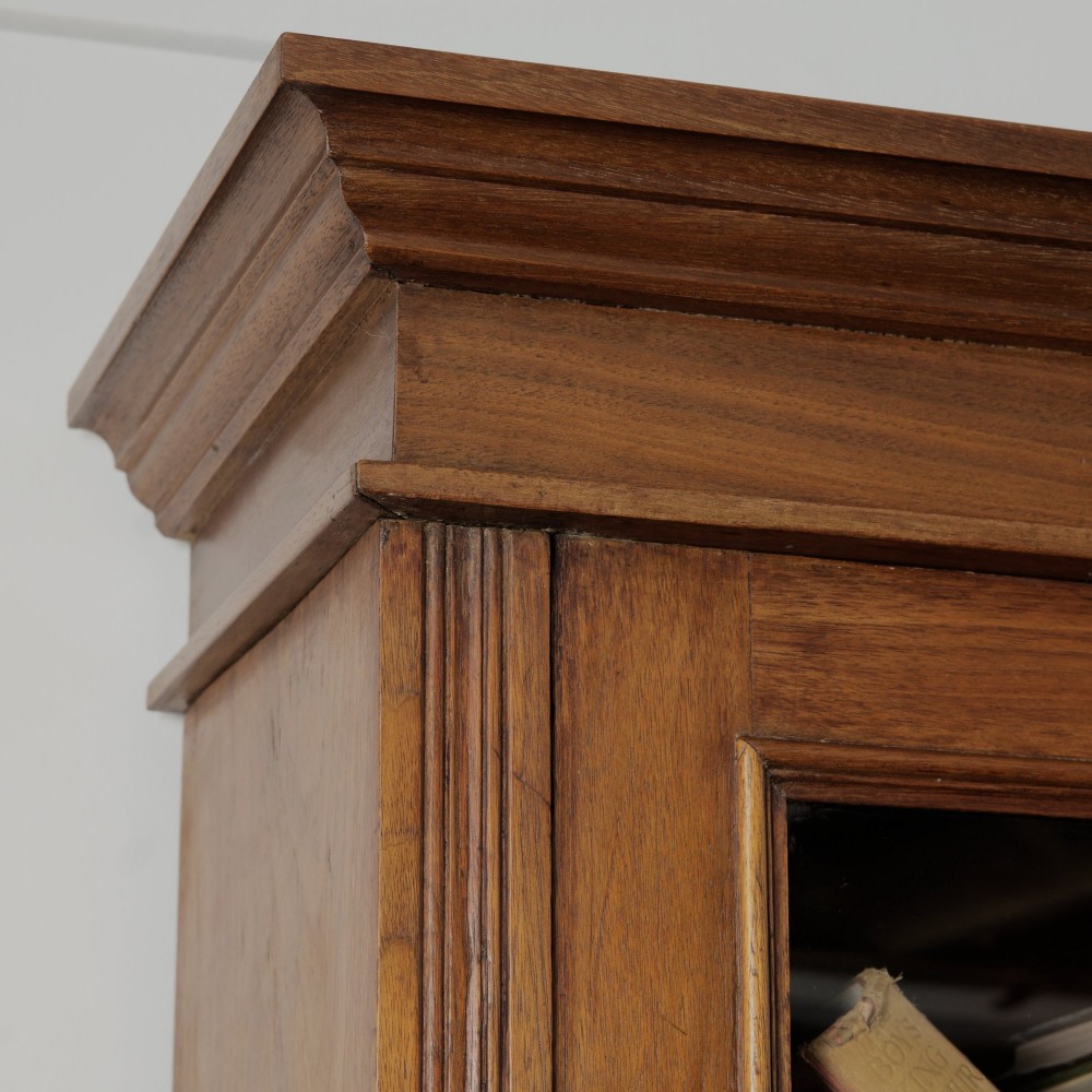 A late Victorian wooden glazed bookcase featuring two upper glass doors above two drawers and a double-door cupboard carved with floral urn motifs. View XI