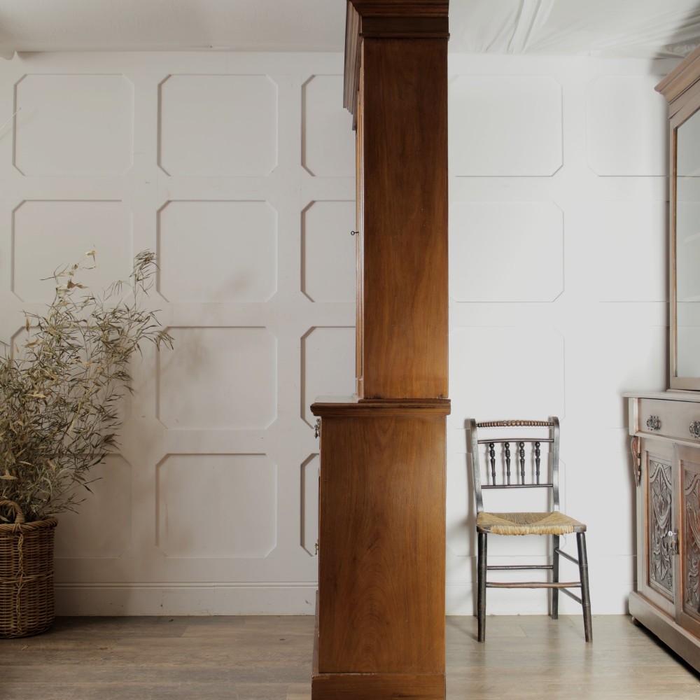 A late Victorian wooden glazed bookcase featuring two upper glass doors above two drawers and a double-door cupboard carved with floral urn motifs. View XIII