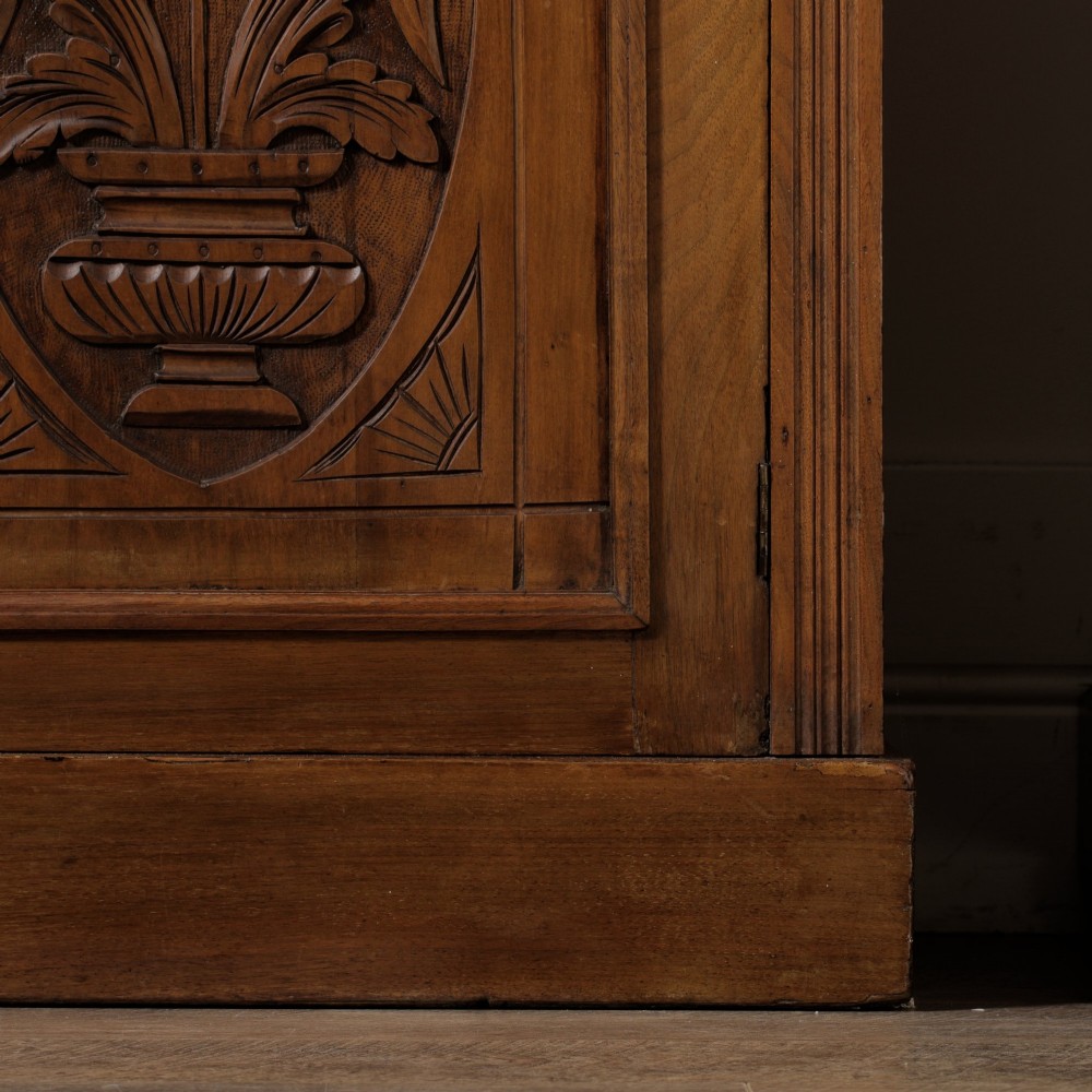 A late Victorian wooden glazed bookcase featuring two upper glass doors above two drawers and a double-door cupboard carved with floral urn motifs. View XIV