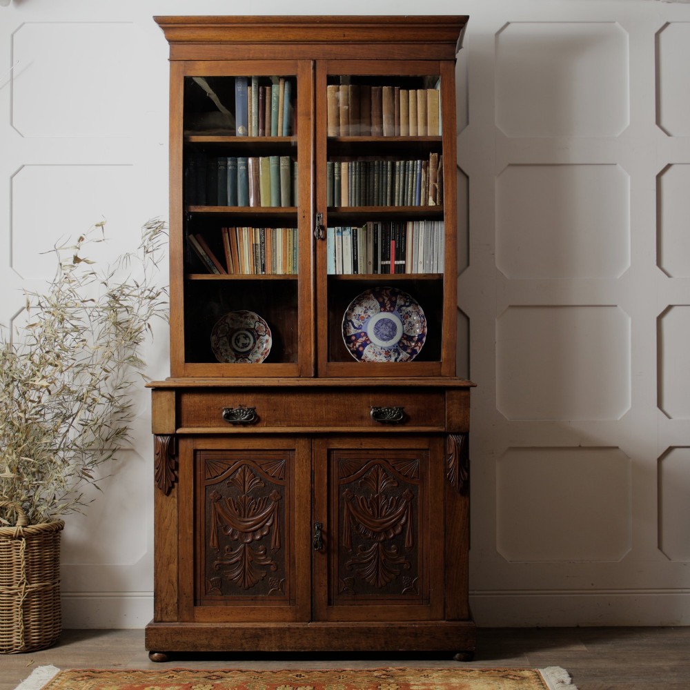 A mid-Victorian mahogany bookcase featuring a two-door glazed upper section, a single frieze drawer, and a lower cupboard with carved panel doors. View II