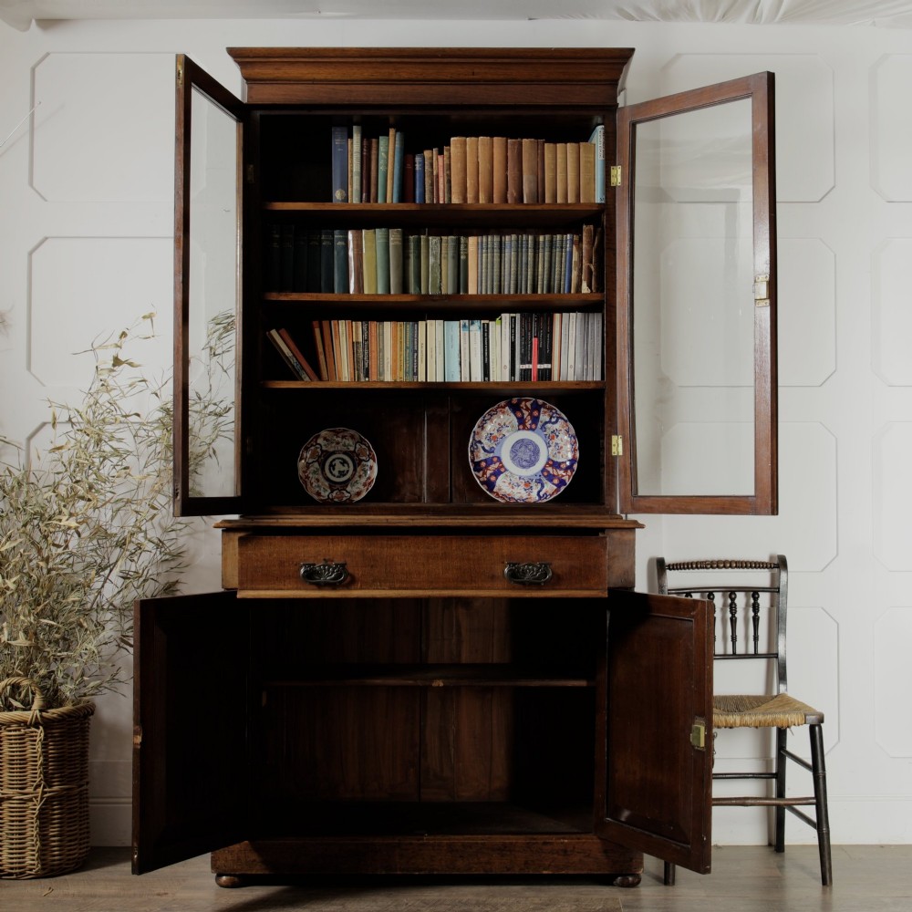 A mid-Victorian mahogany bookcase featuring a two-door glazed upper section, a single frieze drawer, and a lower cupboard with carved panel doors. View III
