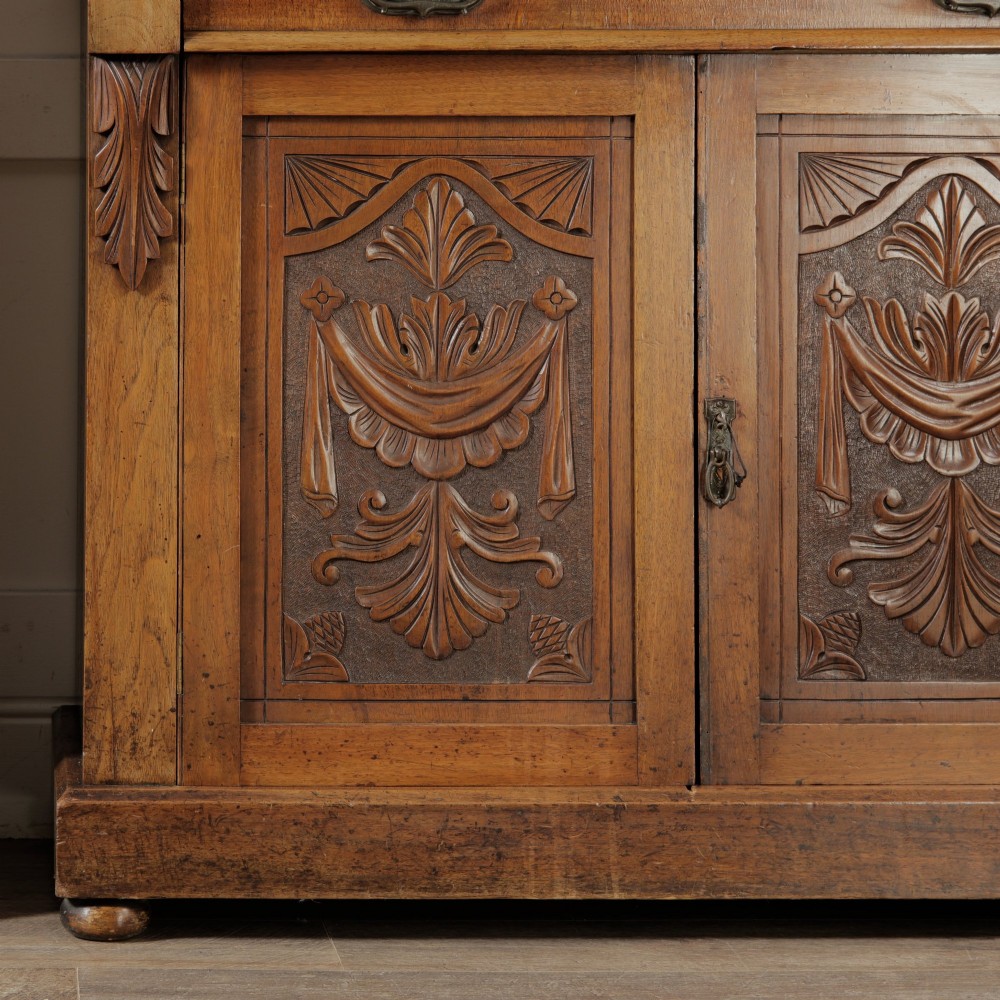 A mid-Victorian mahogany bookcase featuring a two-door glazed upper section, a single frieze drawer, and a lower cupboard with carved panel doors. View IV