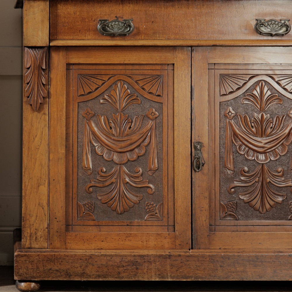 A mid-Victorian mahogany bookcase featuring a two-door glazed upper section, a single frieze drawer, and a lower cupboard with carved panel doors. View V