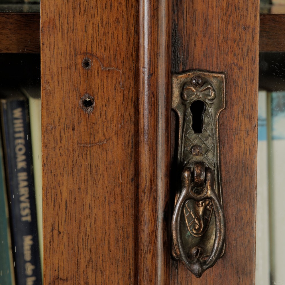 A mid-Victorian mahogany bookcase featuring a two-door glazed upper section, a single frieze drawer, and a lower cupboard with carved panel doors. View VIII
