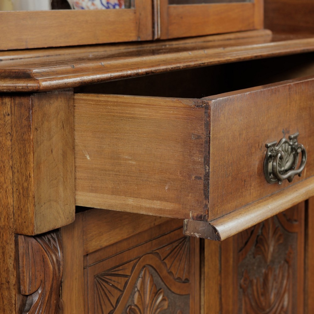 A mid-Victorian mahogany bookcase featuring a two-door glazed upper section, a single frieze drawer, and a lower cupboard with carved panel doors. View IX