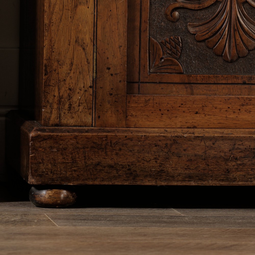 A mid-Victorian mahogany bookcase featuring a two-door glazed upper section, a single frieze drawer, and a lower cupboard with carved panel doors. View X