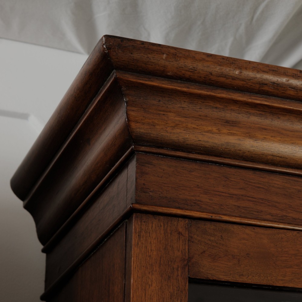 A mid-Victorian mahogany bookcase featuring a two-door glazed upper section, a single frieze drawer, and a lower cupboard with carved panel doors. View XI