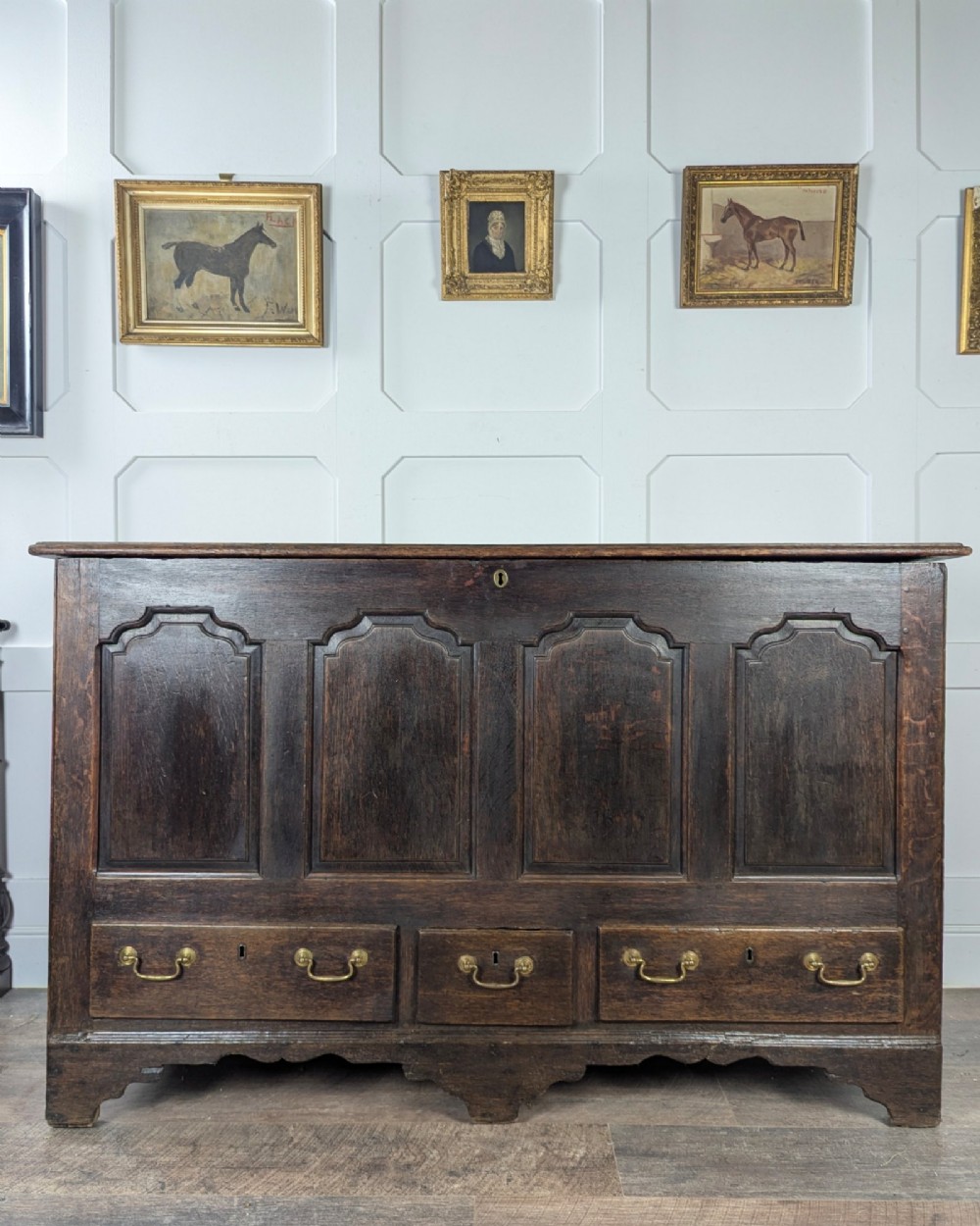 An 18th-century dark oak mule chest featuring four fielded front panels above three small drawers with brass handles. View VII