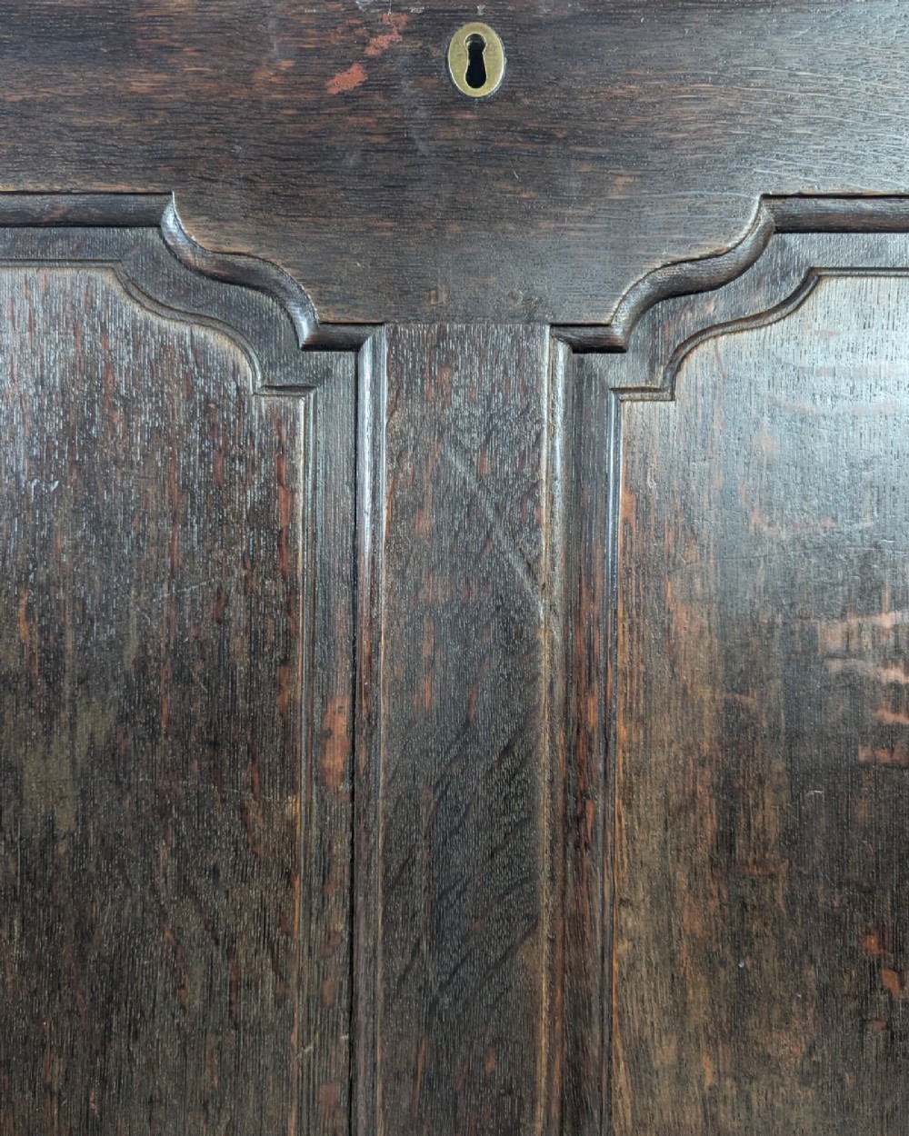An 18th-century dark oak mule chest featuring four fielded front panels above three small drawers with brass handles. View XI