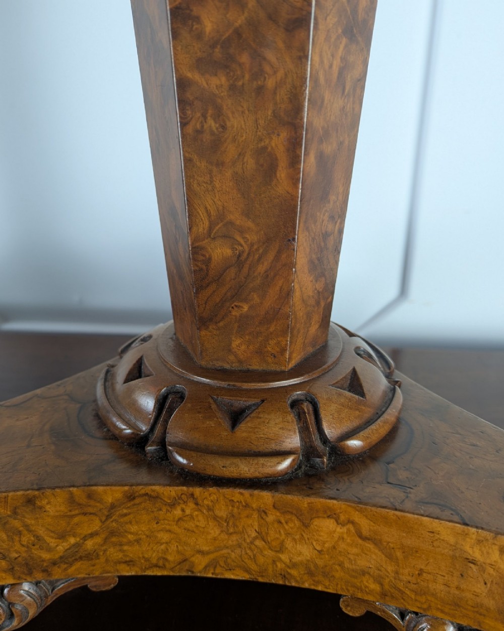 An antique William IV figured walnut revolving piano stool featuring an olive green upholstered square seat, a faceted column, and a carved triform base with scroll feet. View VI