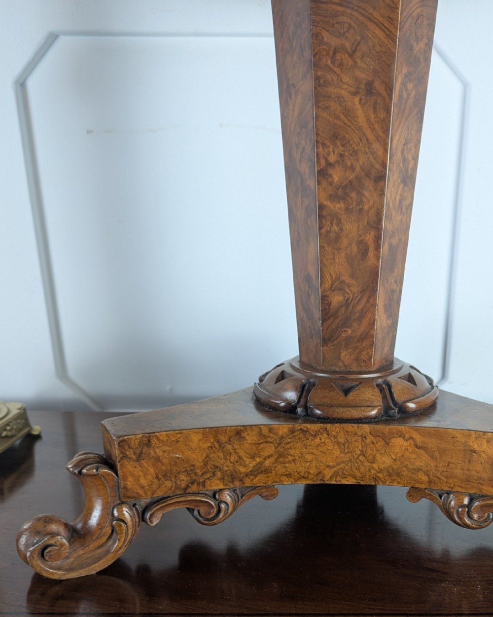 An antique William IV figured walnut revolving piano stool featuring an olive green upholstered square seat, a faceted column, and a carved triform base with scroll feet. View VIII