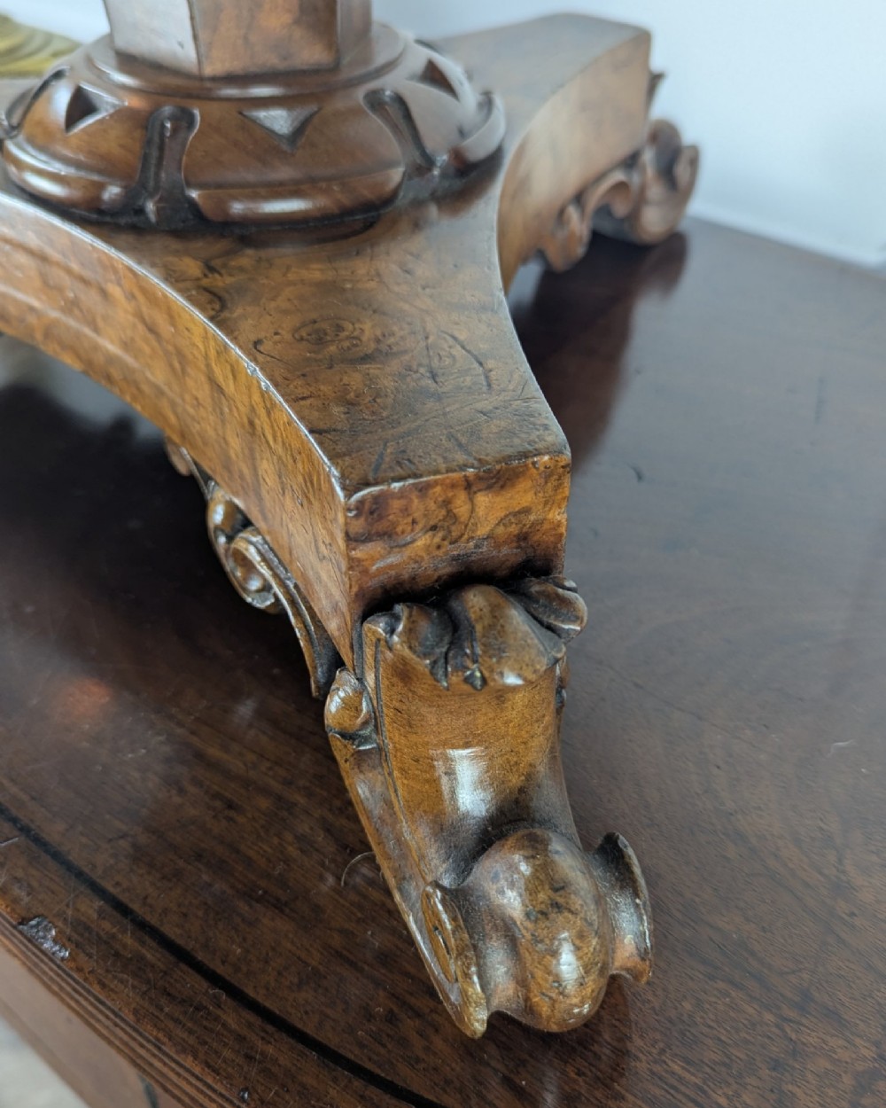 An antique William IV figured walnut revolving piano stool featuring an olive green upholstered square seat, a faceted column, and a carved triform base with scroll feet. View IX