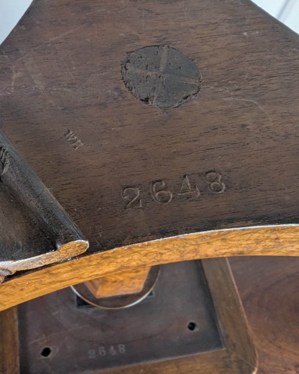 An antique William IV figured walnut revolving piano stool featuring an olive green upholstered square seat, a faceted column, and a carved triform base with scroll feet. View XIII