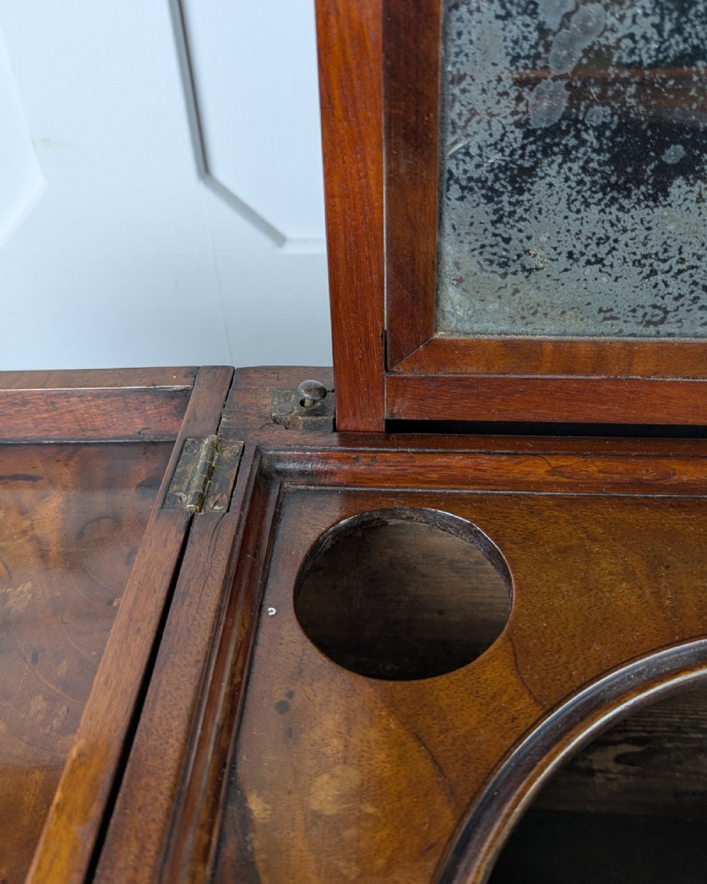 A Georgian Cuban mahogany fold-away washstand featuring an upright mirror, opened side leaves, a central cupboard, a lower drawer, and an X-frame stretcher. View XIV