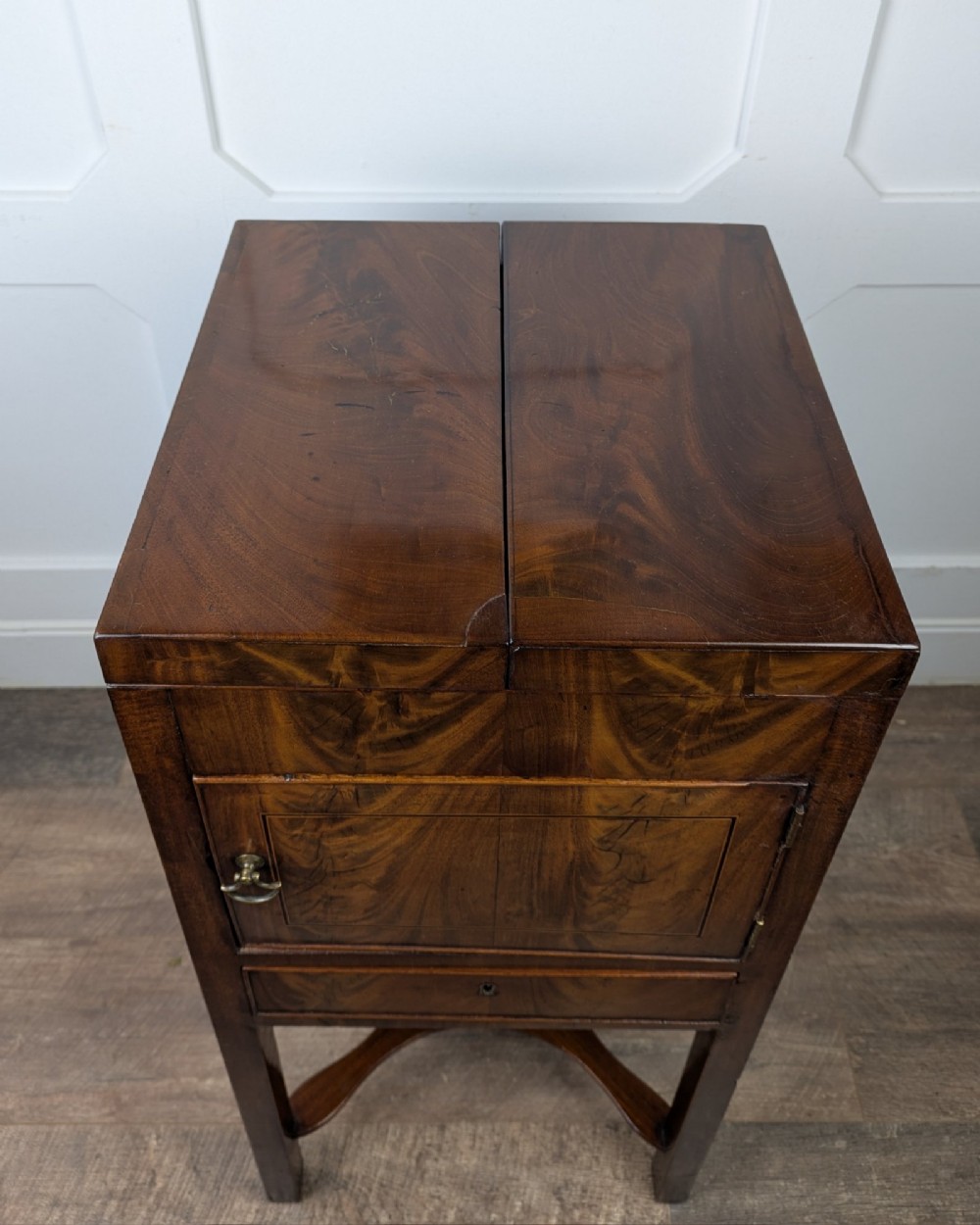 A Georgian Cuban mahogany fold-away washstand featuring an upright mirror, opened side leaves, a central cupboard, a lower drawer, and an X-frame stretcher. View XV