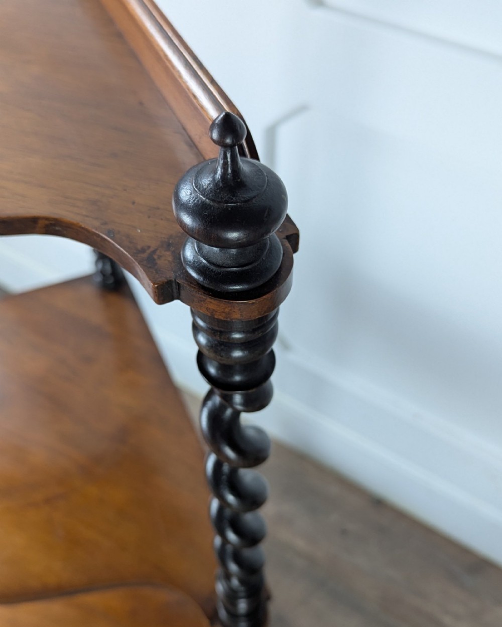 A Victorian dark mahogany three-tier corner whatnot featuring spiralled barley twist front supports and finial details. View VI
