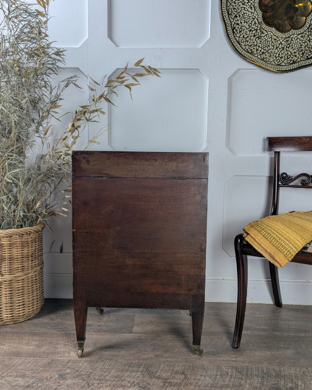 A Georgian dark mahogany cellarette featuring a hinged top lid, a lower drawer with wooden turned knobs, brass side handles, and square tapered legs on brass castors. View III
