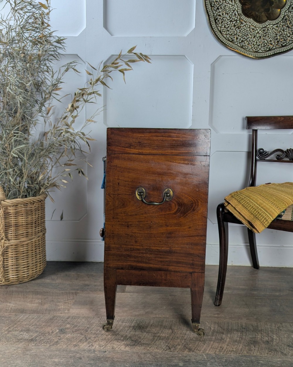 A Georgian dark mahogany cellarette featuring a hinged top lid, a lower drawer with wooden turned knobs, brass side handles, and square tapered legs on brass castors. View IV