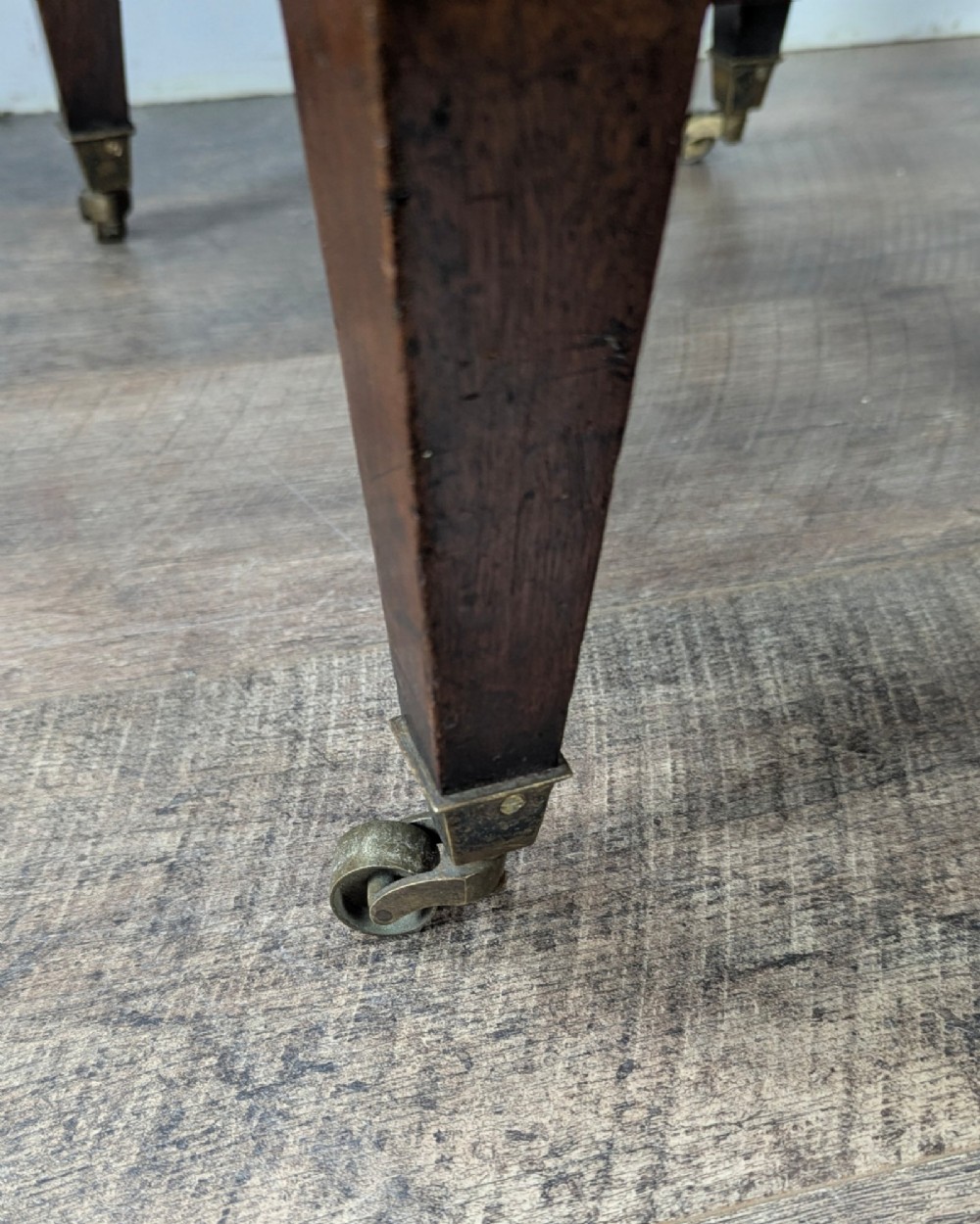 A Georgian dark mahogany cellarette featuring a hinged top lid, a lower drawer with wooden turned knobs, brass side handles, and square tapered legs on brass castors. View X