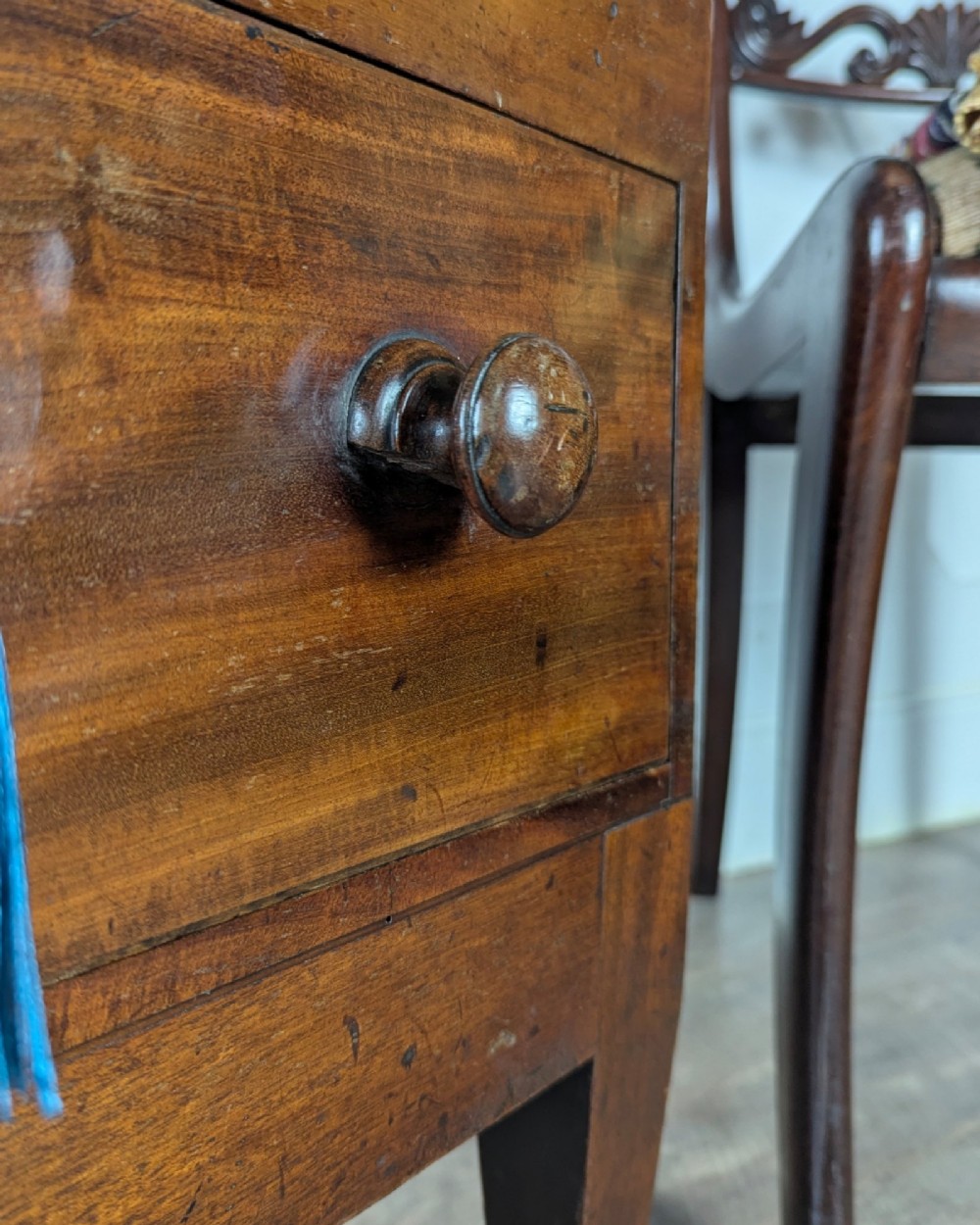 A Georgian dark mahogany cellarette featuring a hinged top lid, a lower drawer with wooden turned knobs, brass side handles, and square tapered legs on brass castors. View XII