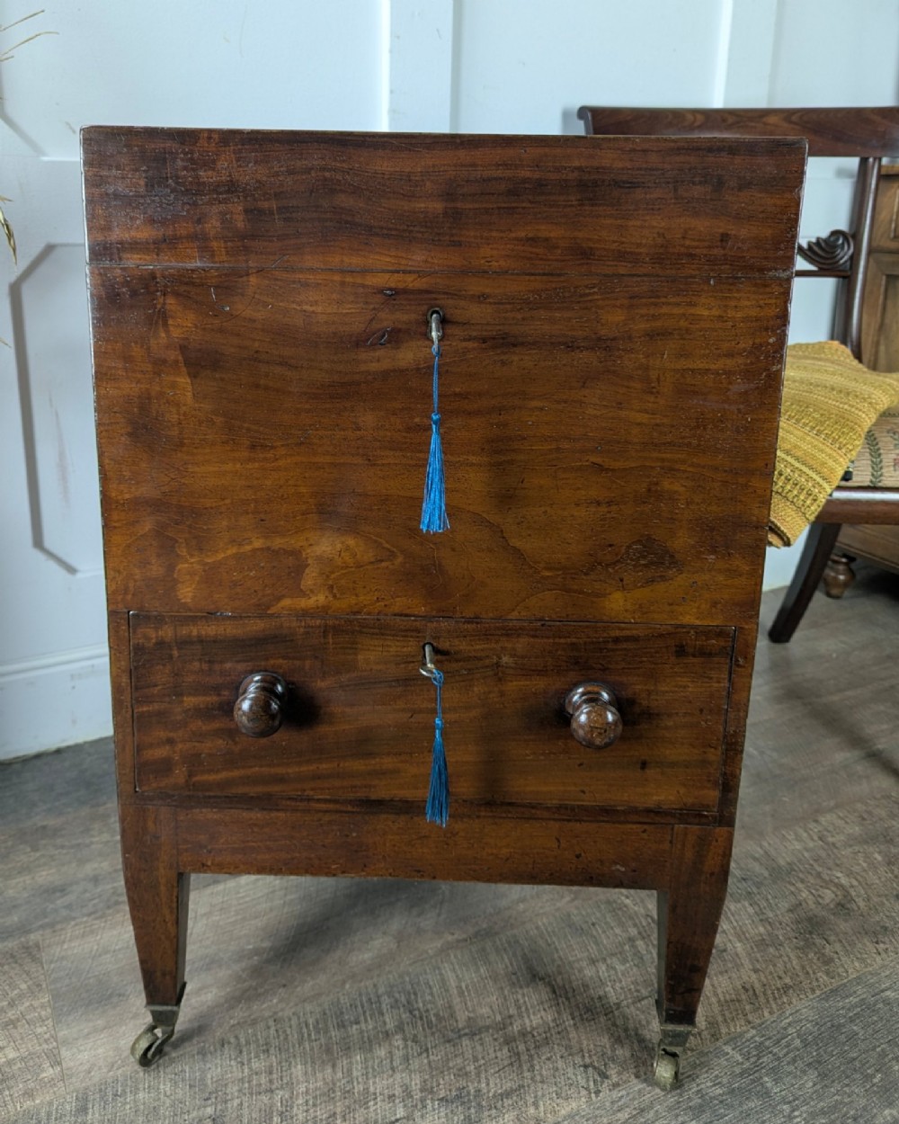 A Georgian dark mahogany cellarette featuring a hinged top lid, a lower drawer with wooden turned knobs, brass side handles, and square tapered legs on brass castors. View XIII