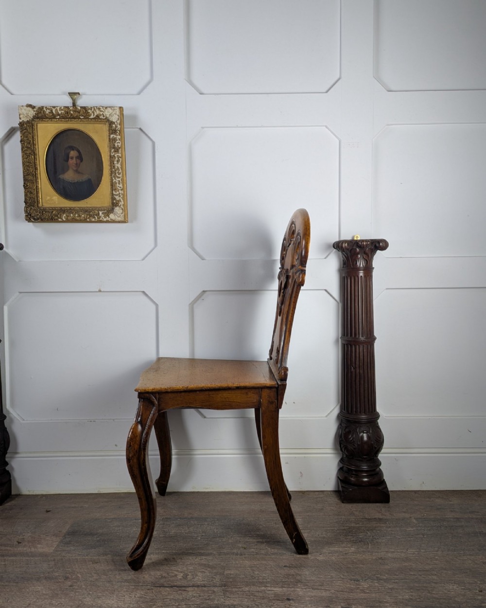A Victorian carved solid oak hall chair featuring an openwork shield back, a solid timber seat, and shaped cabriole front legs. View VI
