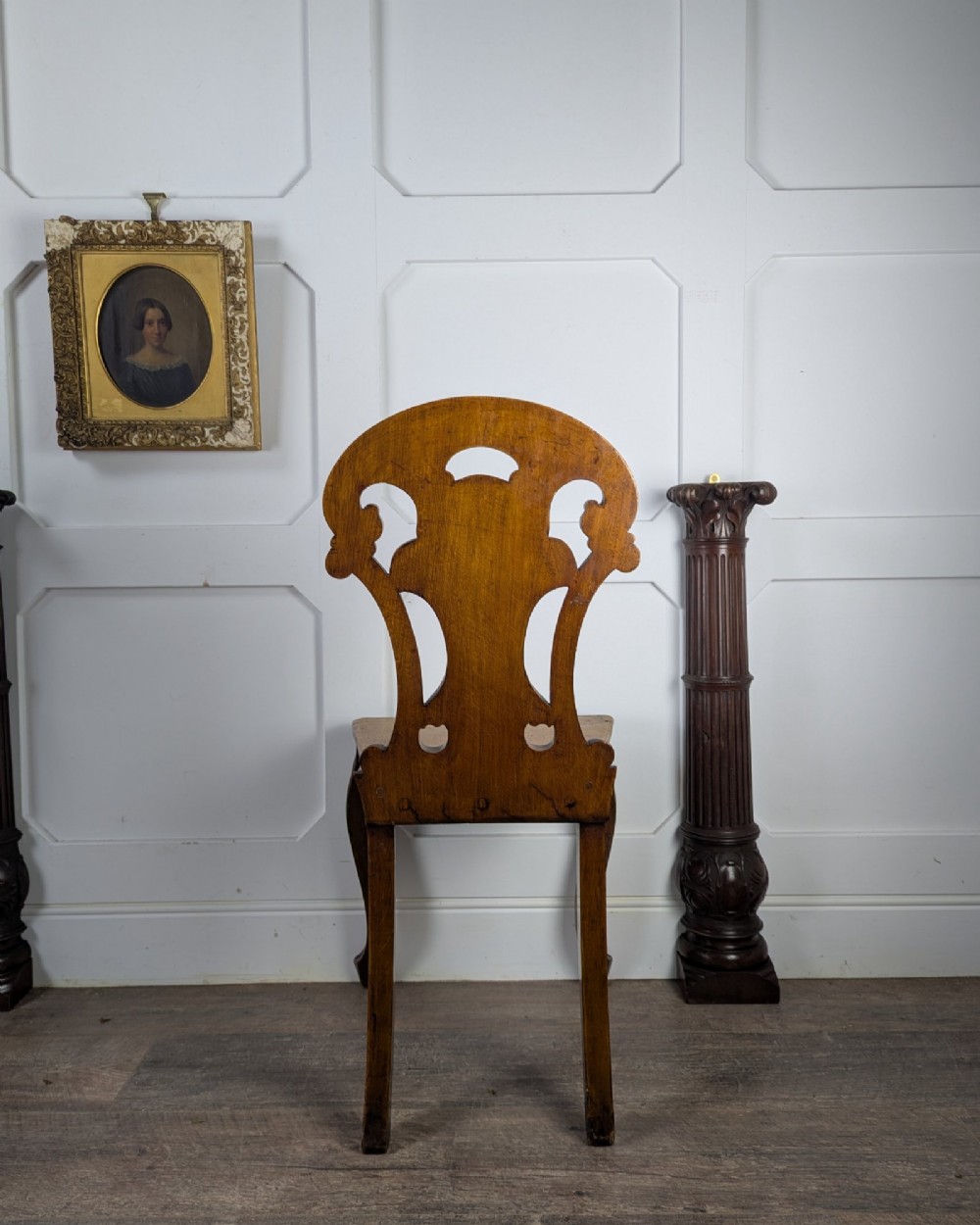 A Victorian carved solid oak hall chair featuring an openwork shield back, a solid timber seat, and shaped cabriole front legs. View VII