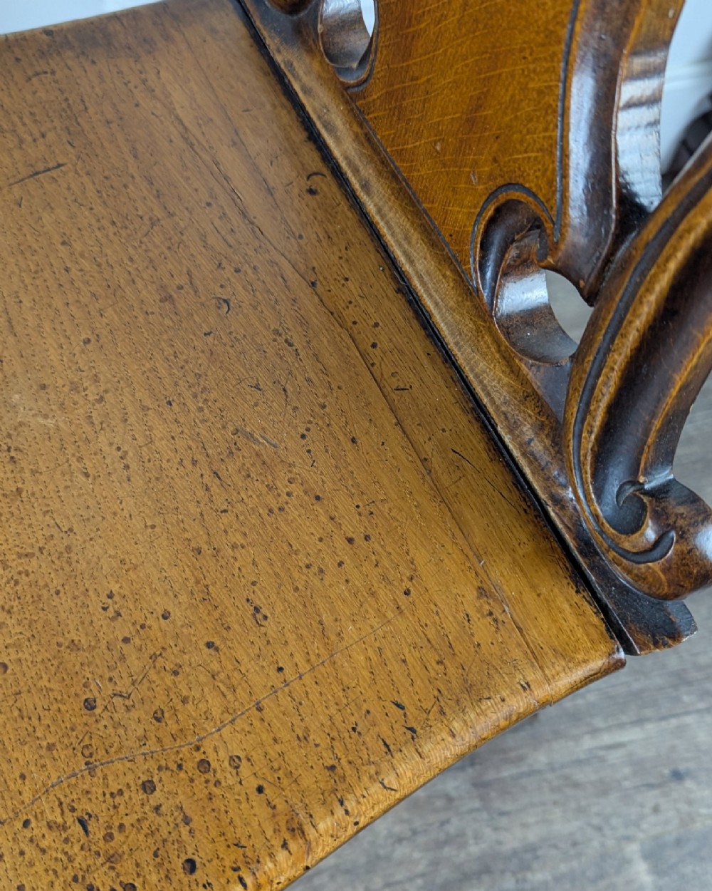 A Victorian carved solid oak hall chair featuring an openwork shield back, a solid timber seat, and shaped cabriole front legs. View X