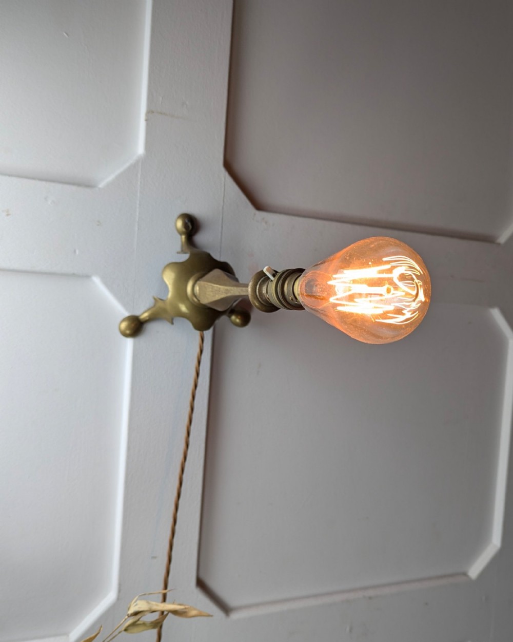 An antique brass table lamp featuring a hexagonal baluster stem resting on a three-legged cast base. View V