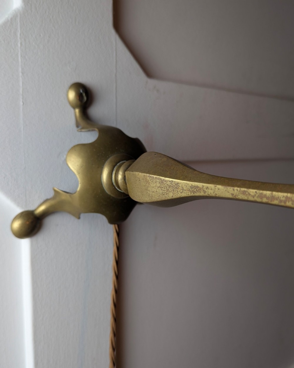 An antique brass table lamp featuring a hexagonal baluster stem resting on a three-legged cast base. View VI