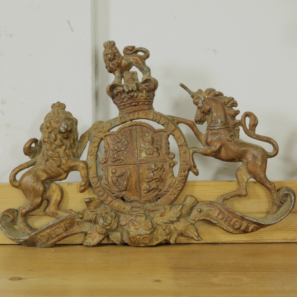 A Victorian cast metal relief plaque depicting the Royal Coat of Arms of the United Kingdom flanked by a lion and unicorn.