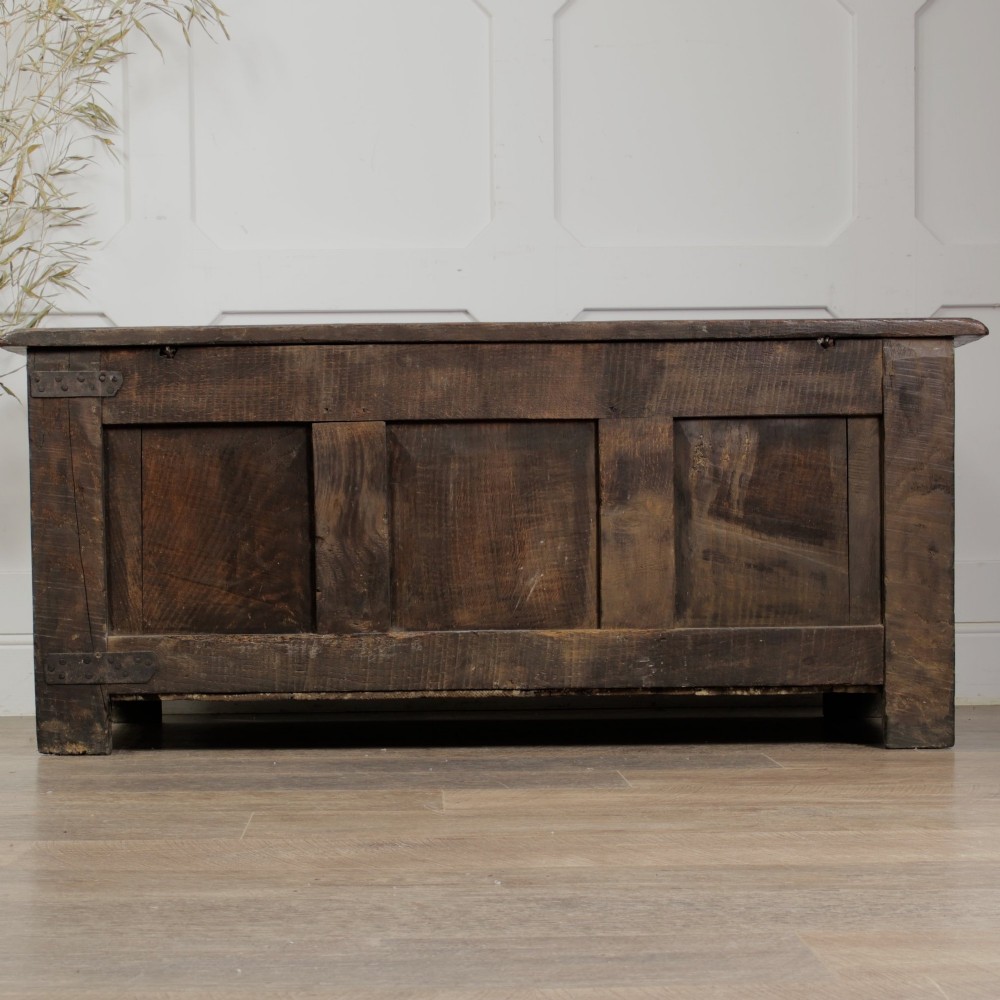 A dark oak panelled chest featuring detailed floral and foliage relief carvings, a central panel inscribed TS 1690, and an iron lockplate. View VI