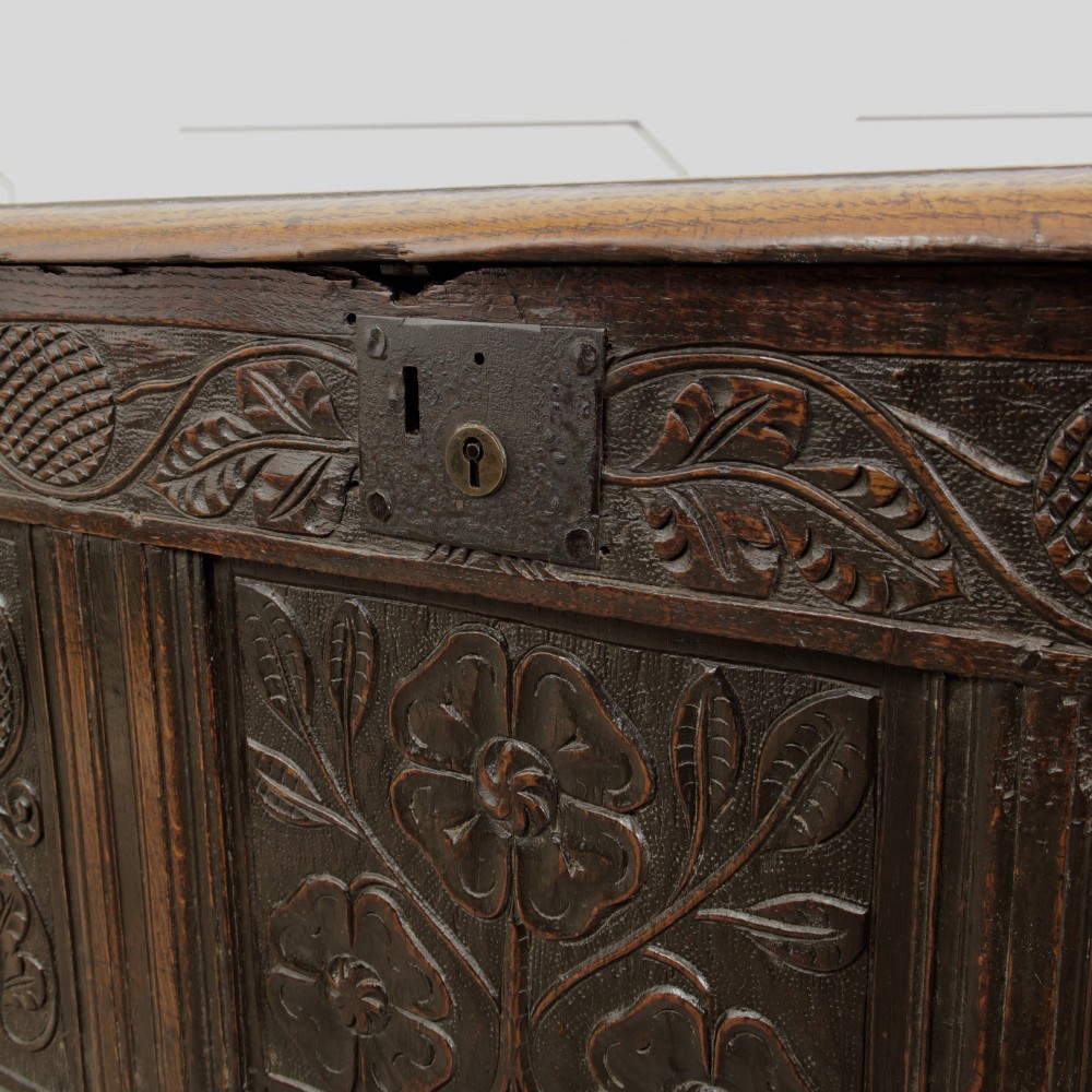 A dark oak panelled chest featuring detailed floral and foliage relief carvings, a central panel inscribed TS 1690, and an iron lockplate. View XI