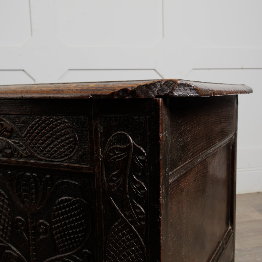 A dark oak panelled chest featuring detailed floral and foliage relief carvings, a central panel inscribed TS 1690, and an iron lockplate. View XII