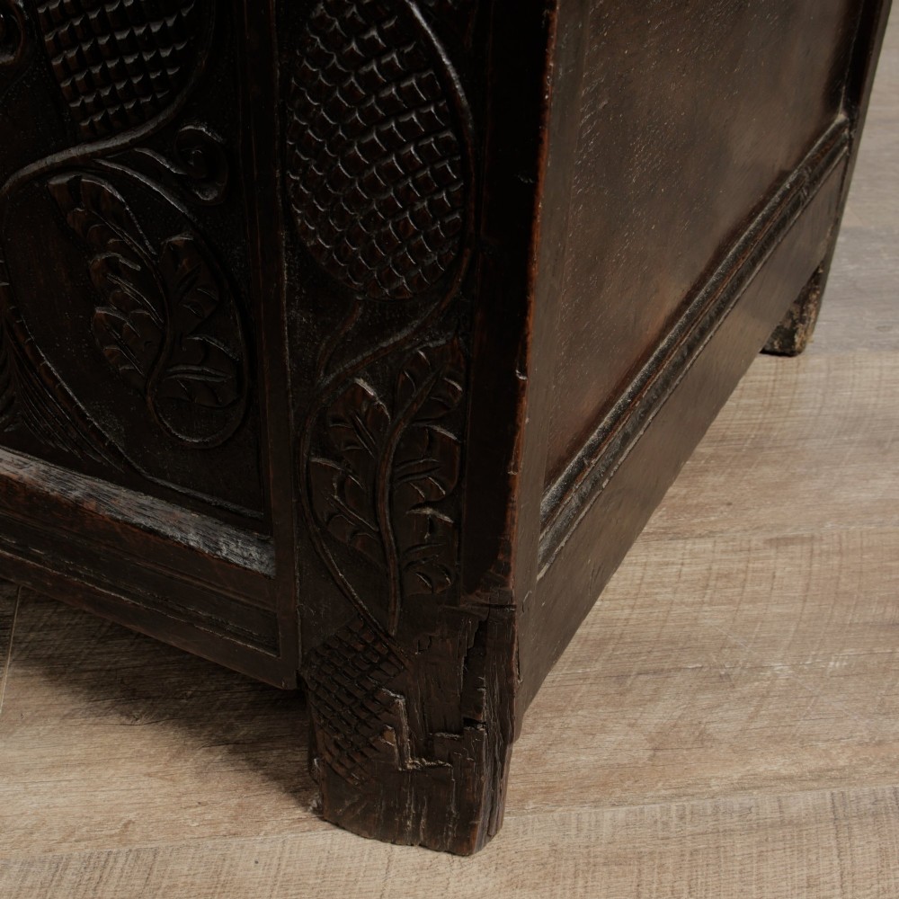 A dark oak panelled chest featuring detailed floral and foliage relief carvings, a central panel inscribed TS 1690, and an iron lockplate. View XIII