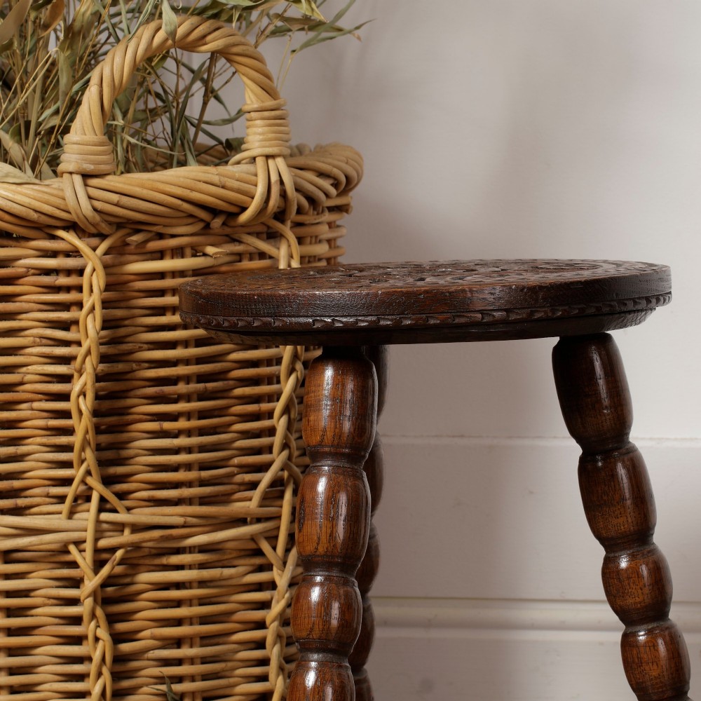 An early twentieth-century dark oak three-legged milking stool featuring turned legs and a carved round seat. View VI